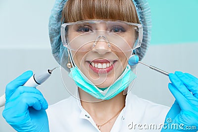 Young female dentist treating patient's teeth by filling cavity. Dentist works Stock Photo