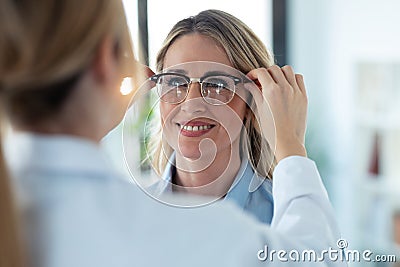 Young female doctor choosing while proving eyeglasses to mature beautiful patient in medical consultation Stock Photo