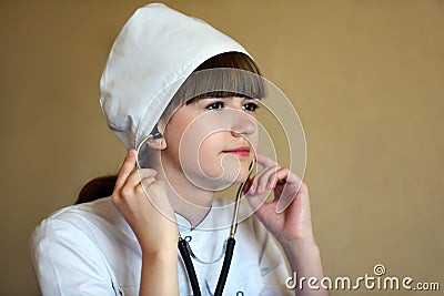 A young female doctor inserts a stethoscope in her ears. Stock Photo