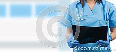 Young female doctor with stethoscope looking at patients x-ray Stock Photo