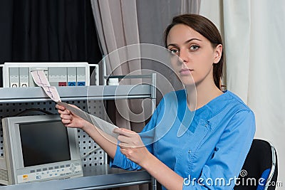 Young female doctor in uniform is holding analysis of electrocardiogram examination Stock Photo