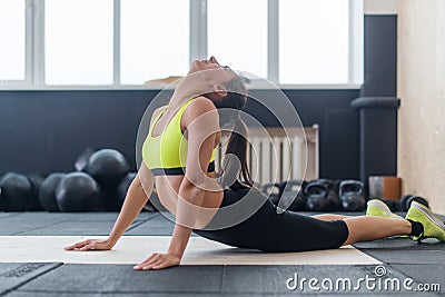 Young female doing back stretching exercise, fit woman warming-up in gym Stock Photo