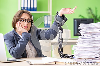 The young female employee busy with ongoing paperwork chained to the desk Stock Photo