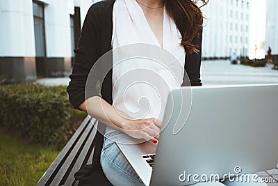 Young female freelancer making labor market research on modern laptop, sits on outdoors in urban street Stock Photo