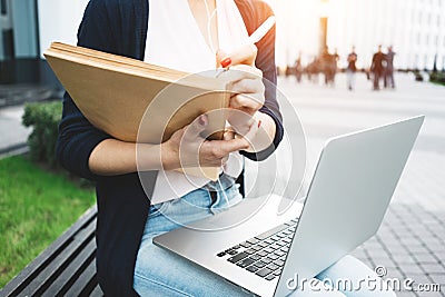 Young female freelancer making labor market research on modern laptop, sits on outdoors in urban street Stock Photo