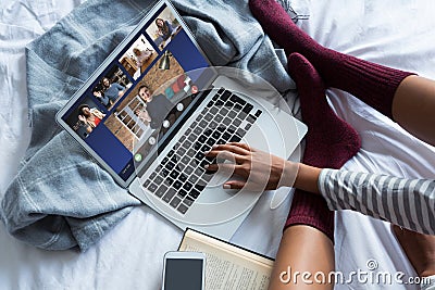 Young female freelancer video chatting with colleagues while working on bed at home Stock Photo