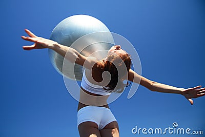 Young female gymnast with yoga ball on her chest Stock Photo