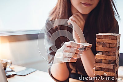 Young female hand placing or pulling wooden block on the tower balance game. Business planning, Risk Management, Mission, Solution Stock Photo
