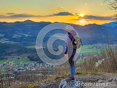 Young female hiker stands on top of hill with her senior dog inside her backpack Stock Photo