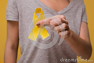 Young female holding yellow gold ribbon awareness symbol for endometriosis, suicide prevention, sarcoma bone cancer Stock Photo