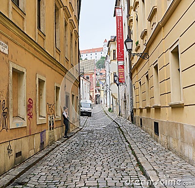 Young Female Hospitality Worker takes smoke break in cobblestone side street, Bratislava, Slovakia. Editorial Stock Photo