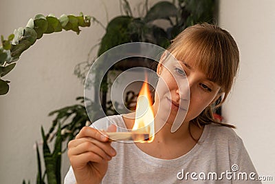 Young female looking how aroma wooden stick burning. Aromatherapy incense practice Stock Photo