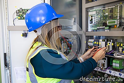 Young female maintenance engineer testing voltage with digital multimeter Stock Photo