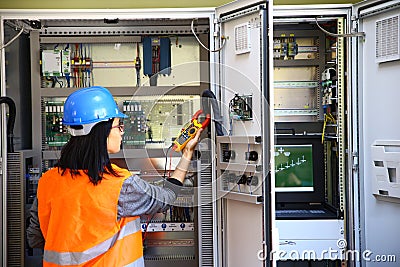 Young female maintenance engineer testing voltage with digital multimeter Stock Photo