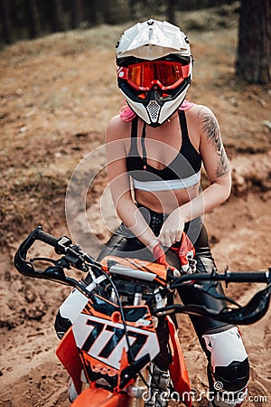 Young female motocross racer in safety helmet riding on her motorcycle in off road adventure Stock Photo