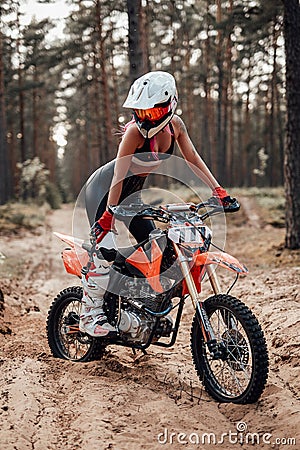 Young female motocross racer in safety helmet riding on her motorcycle in off road adventure Stock Photo