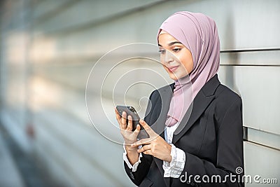 Young Female Muslim Entrepreneur looking at her smartphone Stock Photo