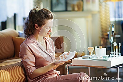 Young female with no makeup looking at white sheet facial mask Stock Photo
