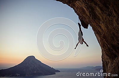 Young female rock climber hanging on rope upside down while being lowered down Stock Photo