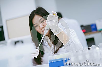 Young scientists using pipette to transfer sample in test tube Stock Photo