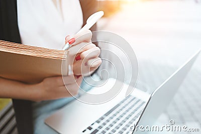 Young female student prepares for thesis sits on outdoors in urban space near university. Business woman work during the lunch bre Stock Photo