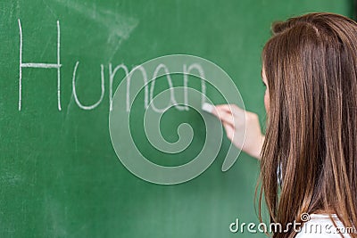 Young female teacher teaching in biology class. Teacher writing Human Body on blackboard. Stock Photo