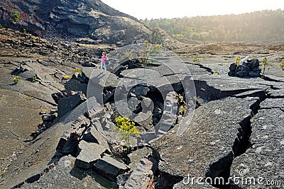 Young female tourist exploring surface of the Kilauea Iki volcano crater with crumbling lava rock in Volcanoes National Park in Bi Stock Photo