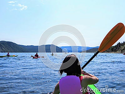 A young female tourist in a kayak exploring the beautiful waters in Bonne Bay with a group of kakayers, in Gros Morne Stock Photo