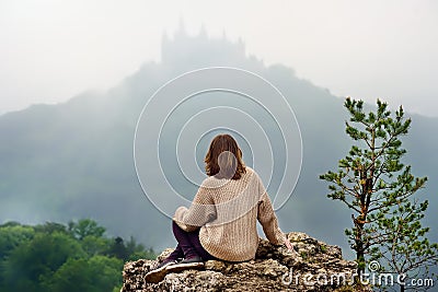 Young female tourist looking on famous Hohenzollern Castle in thick fog, Germany Stock Photo