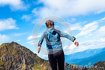 A young female tourist on top of a mountain jumps into the sky. Happiness and a sense of freedom, Stock Photo