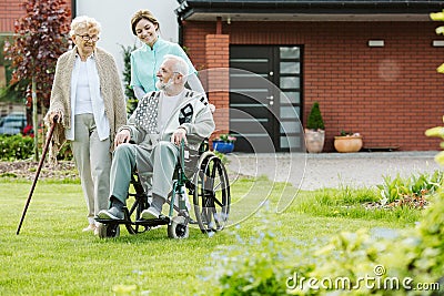 Young female trainee with elder couple in the garden Stock Photo