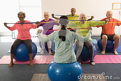 Young female trainer and senior people exercising with resistance band Stock Photo