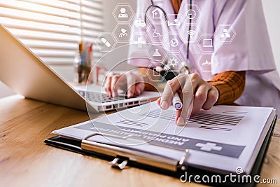 Young female in uniform of doctor using digital technology laptop for Output Device and writing a patient report on the office des Stock Photo