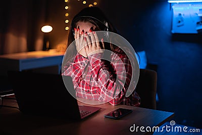 Young female watching scary movie, hiding face in fear. Horror movie at home. Online film service Stock Photo