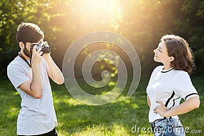 Young female wearing T-shirt and jeans posing in camera to photographer. Young talented male with retro camera photographing prett Stock Photo