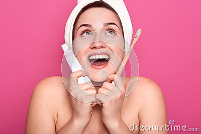 Young female with white towel on head an d nacked shoulders, ready for brushing teeth, looking up with open mouth and happy facial Stock Photo