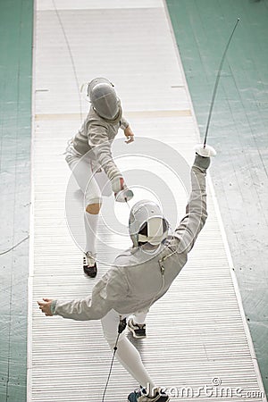 Young fencers in protective costumes fighting on the fencing competition Stock Photo