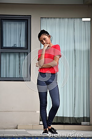 Thinking Young Filipina Girl Standing By Condo Stock Photo