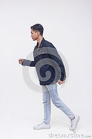 A young filipino man walking in an exaggerated way. Active dynamic teenager in motion. Isolated on a white backdrop Stock Photo