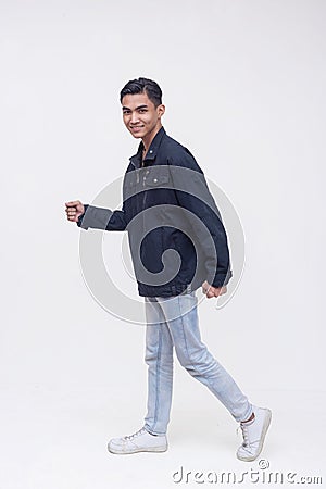 A young filipino man walking in an exaggerated way. Active dynamic teenager in motion looking at the camera. Isolated on a white Stock Photo