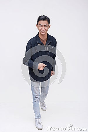 A young filipino man walking forward in an exaggerated way. Active dynamic teenager in motion. Isolated on a white backdrop Stock Photo