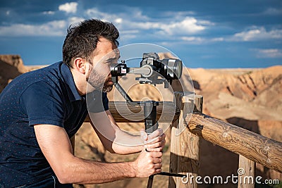 Young filmmaker filming natural landscape in canyon with a large river and marshes Stock Photo