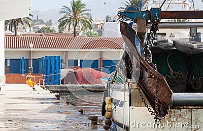 A young fisherman pulls himself with the only help of his muscular strength a boat in a fishing port pulling a thick rope Editorial Stock Photo