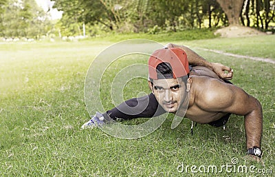 Young fit Caucasian man with muscular body doing push-ups outdoors on sunny summer day Stock Photo