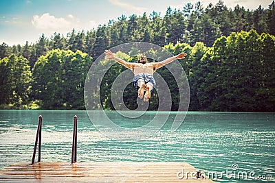 Young fit man making a jump into a lake. Stock Photo