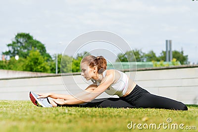 Young, fit and sporty woman stretching in the park. Fitness, sport, urban and healthy lifestyle concept. Stock Photo