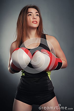 Young fitness girl with bloxing gloves looking at camera over black background art Stock Photo