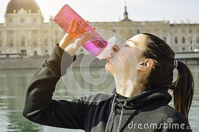 Young fitness woman drinking water after training in the city Stock Photo