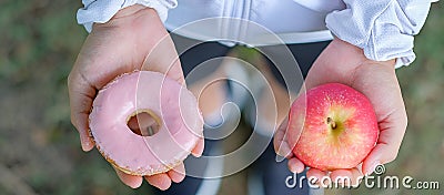 Young fitness woman holding in hands red apple and donut Stock Photo