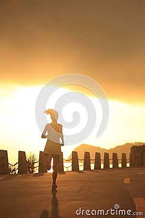 Young fitness woman running on sunrise seaside Stock Photo